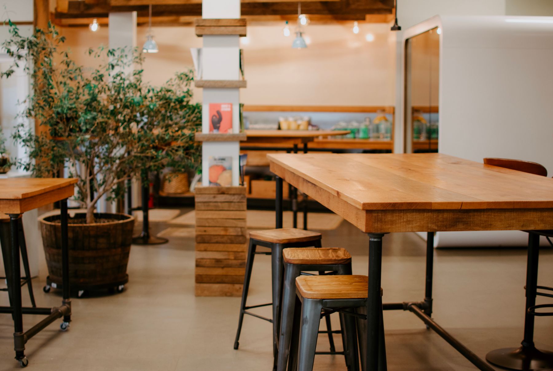 Co-working lounge with communal wood tables, stools and a call booth